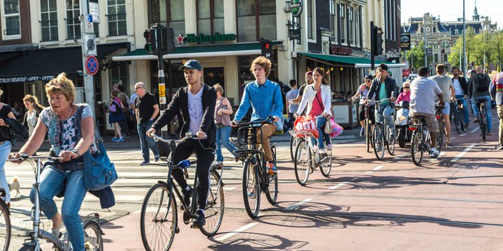 AMSTERDAM, THE NETHERLANDS - JUNE 16, 2016: People riding bicycles in historical part of Amsterdam in a beautiful summer day, The Netherlands on June 16, 2016
