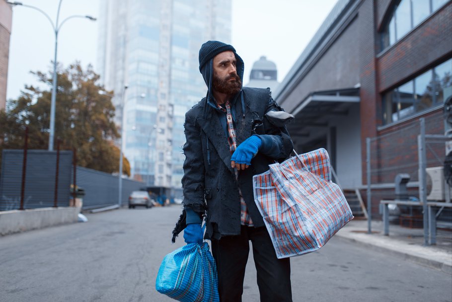 Bearded tramp man with bag on city street