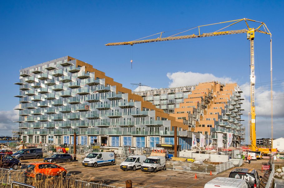 Amsterdam, The Netherlands, February 11, 2022: construction site with crane of the Sluishuis residential building in IJburg neighbourhood under a blue sky