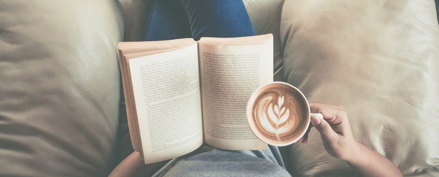 Soft photo of young girl reading a book and drinking coffee